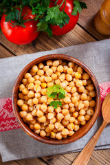 Boiled chickpeas in a wooden bowl on a wooden table, top view, selective focus