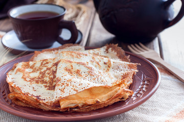 Thin fishnet pancakes on a clay plate, horizontal