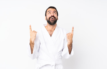 Fototapeta premium Young man doing karate over isolated white background surprised and pointing up