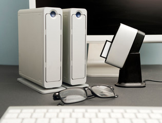 Conceptual work table photographer, composition, silver-colored desktop hard drive with lenses, compact flash card downloader, partial computer view, black background