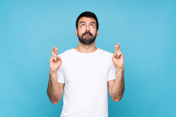 Fototapeta premium Young man with beard over isolated blue background with fingers crossing and wishing the best