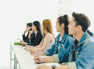 Asians attend seminars and listen to lectures from speakers in the training room. Some people take notes. Some people raised their hands to ask the narrator. 