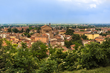 Fototapeta na wymiar View on the roofs of Bergamo, Lombardy, Italy. Cloudy light blue sky above red roofs of medieval city. Spring in italian city. City landscape with rooftops and blooming trees.