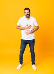 Full-length shot of man with beard over isolated yellow background smiling a lot