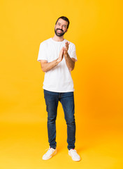 Fototapeta na wymiar Full-length shot of man with beard over isolated yellow background applauding after presentation in a conference