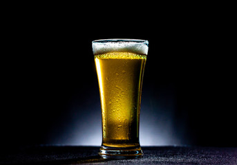 glass of beer with foam on black background