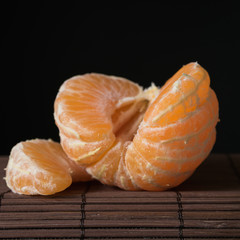still life, slices of ripe juicy mandarin on a black background close-up