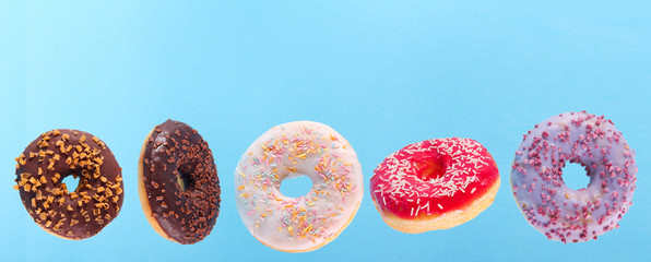 Flying donuts with colorful glaze over blue background