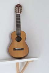 Obraz premium Acoustic guitar isolated on white background. On wooden shelf Minimalist composition