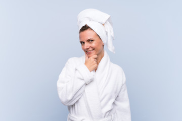 Woman in bathrobe over isolated blue background laughing
