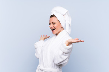 Woman in bathrobe over isolated blue background with surprise facial expression