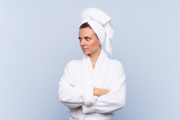 Woman in bathrobe over isolated blue background looking side