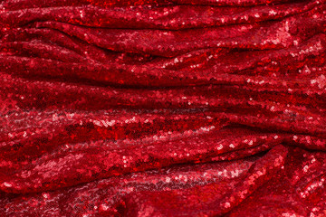 bright red fabric with small round sequins, with metallic sheen laid out by waves for Valentine's day