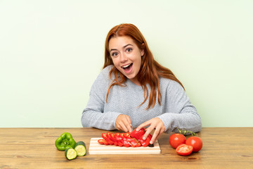 Teenager redhead girl with vegetables in a table