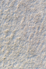 Vertical photography of texture of fresh white snow covering ground thickly on frosty winter morning outside. 