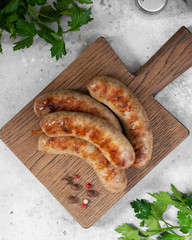 Grilled sausages on a wooden Board on a light gray kitchen table. View top