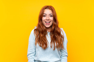 Teenager redhead girl over isolated yellow background with surprise facial expression