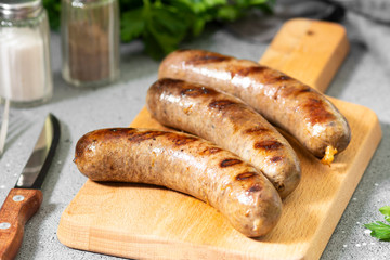Grilled sausages on a wooden Board on a light gray kitchen table