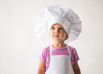 Portrait of a cute little child in a chef's hat on a white background. Concept of children helpers in the kitchen. Advertising space