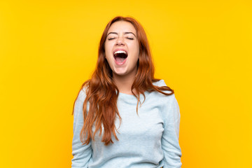 Teenager redhead girl over isolated yellow background shouting to the front with mouth wide open