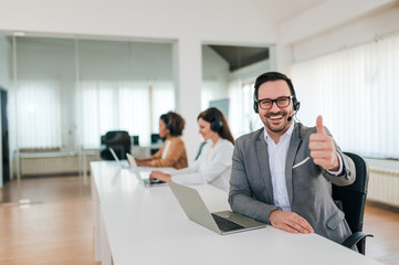 Portrait of a successful customer support phone operator or sales agent showing thumbs-up.