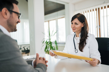 Fototapeta premium Positive doctor and patient on a meeting in medical office, portrait.