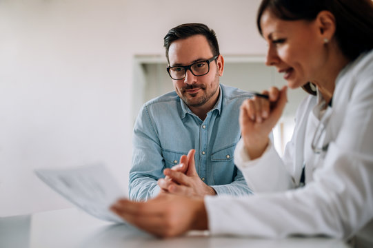 Close-up image of smiling man listening to a female healthcare worker, portrait.