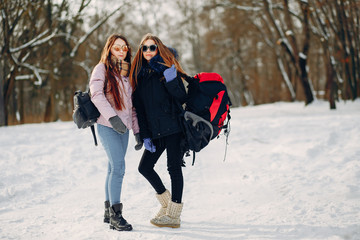 Fototapeta na wymiar two young friends are walking in the winter snow-covered forest