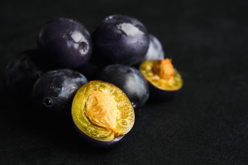 Stack of fresh natural plums over black background