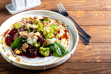 Beetroot carpaccio with walnuts, goat cheese, lettuce and spinach. Dressed with sauce. In a deep...