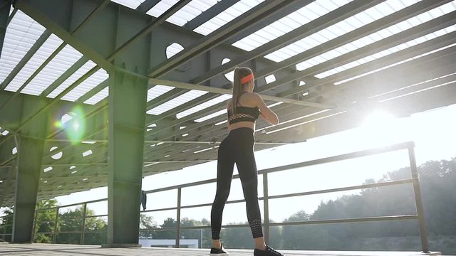 Fitness concept where beautiful slim sporty young woman in sportswear doing squat exercises in the open air ground