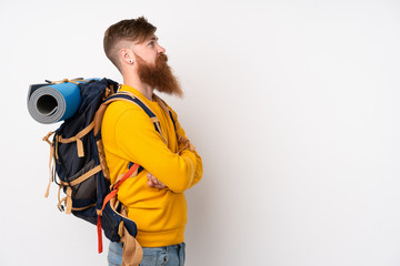 Young mountaineer man with a big backpack over isolated white background looking side