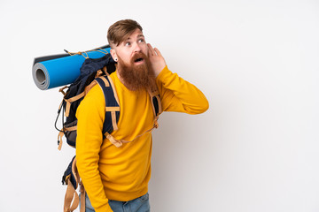 Young mountaineer man with a big backpack over isolated white background listening something