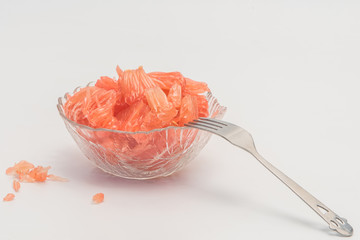 A gold skin red pulp Grapefruit's pulp and silver fork are set on a white background.