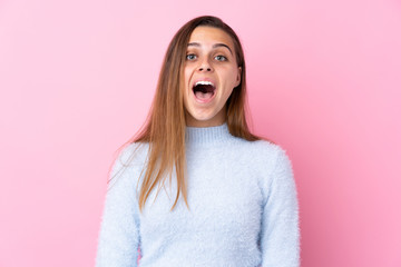 Teenager girl with blue sweater over isolated pink background with surprise facial expression