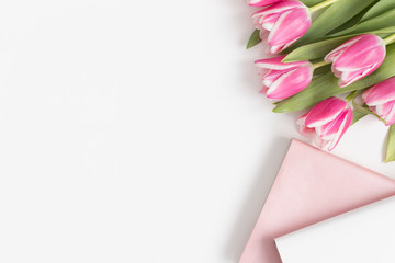 Bouquet of pink tulips and books on a white table. Flat lay with blank copy space.