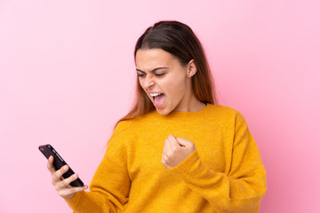 Teenager girl with yellow sweater over isolated pink background surprised and sending a message