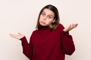 Teenager girl over isolated background having doubts with confuse face expression