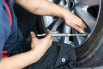 Mechanic checking tire pressure with tyre pressure gauge