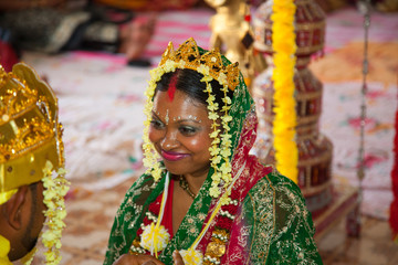 A happy bride smiles at her fiance at a wedding ceremony in a Hindu temple. Indian wedding...