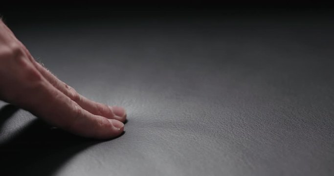 Slow motion man hand touching soft leather cushion