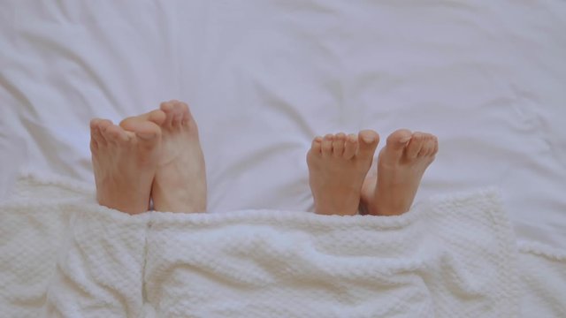 close up woman and man scratch feet in bedroom pair have fun in bed in the morning