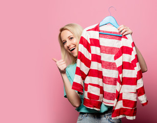 Beautiful woman with shirt on ahanger on pink background