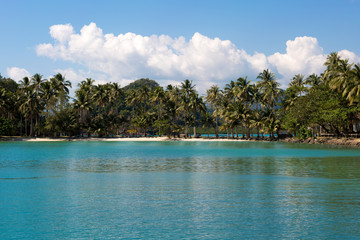 Tropical island sand beach on the sea. Blue sky with clouds.