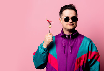 Style guy in glasses with chili pepper on a fork on pink background