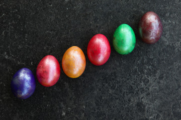 Sechs bunter Eier in schräger Reihe auf anthrazit Fläche