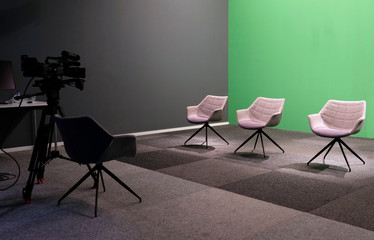 Three empty chairs in a TV studio with green screen
