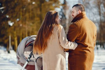 Elegant family in a winter forest. Mother with carriage. Man in a brown coat