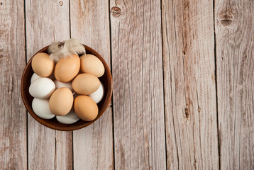 Easter composition. Fresh farm chicken eggs in a clay Cup on a wooden background. Free space.