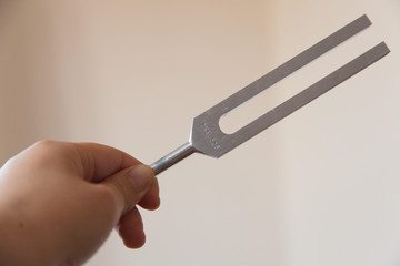 Hand holding a tuning fork and crystal stone  .